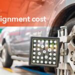 Technician performing a wheel alignment service on a vehicle using alignment equipment.
