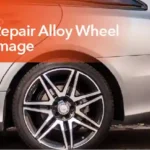 Technician repairing curb damage on an alloy wheel by sanding, filling, and refinishing the rim for a smooth finish.