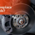 Mechanic inspecting worn brake pads during a routine vehicle brake service.
